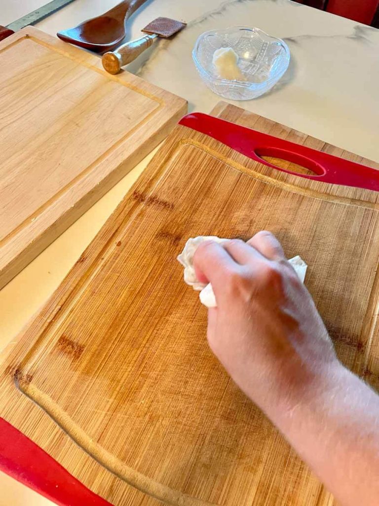 applying coconut oil to a wooden cutting board for deep cleaning