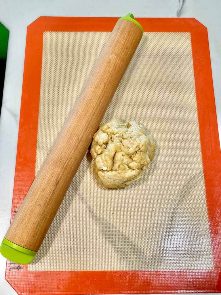 dough and a rolling pin on a silicone baking mat for sourdough crackers