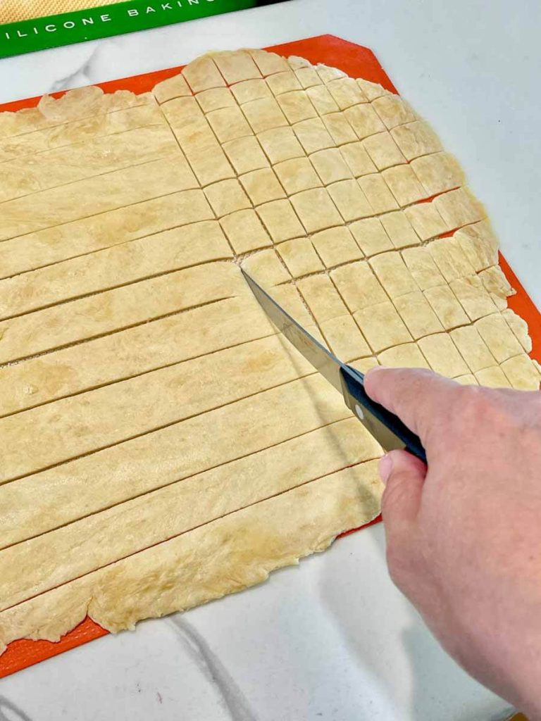 someone cutting dough into squares for sourdough crackers